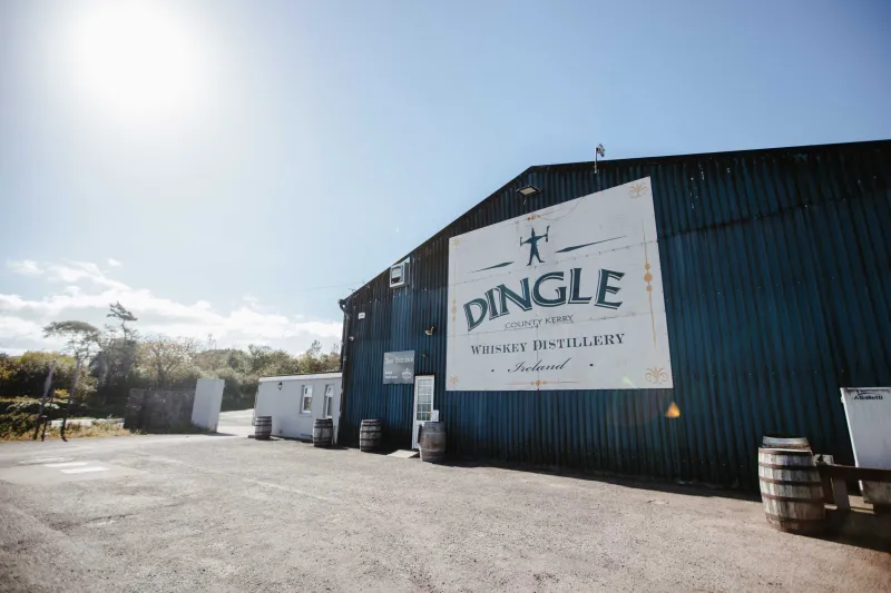 A modern distillery building with corrugated metal siding and a large white sign reading 